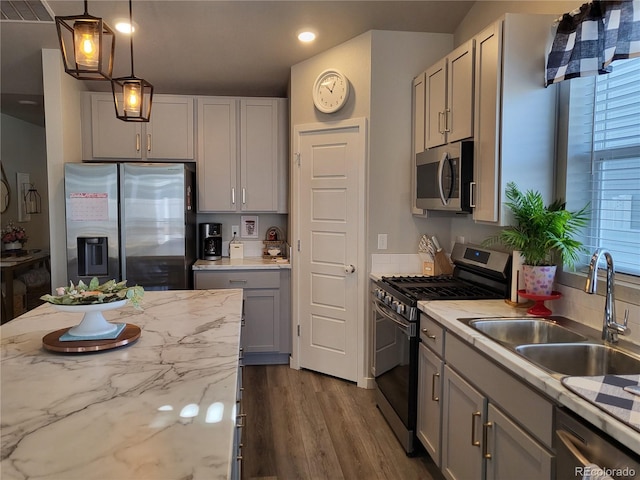 kitchen featuring stainless steel appliances, light stone countertops, sink, and gray cabinetry