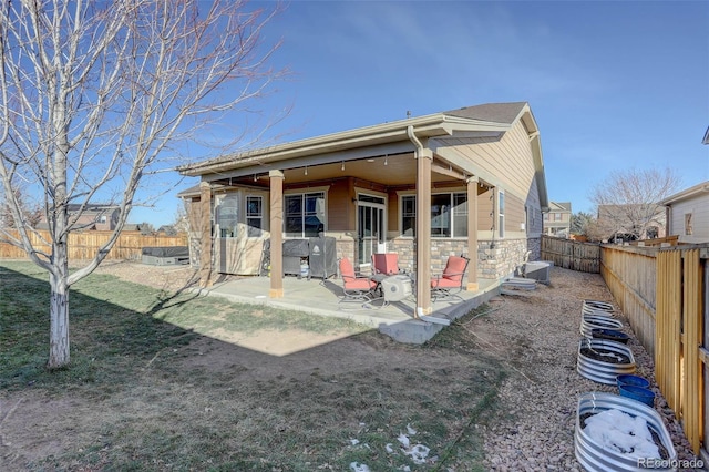 25525 E 1st Ave, Aurora, CO 80018 - back of house featuring stone siding, a patio area, and a fenced backyard