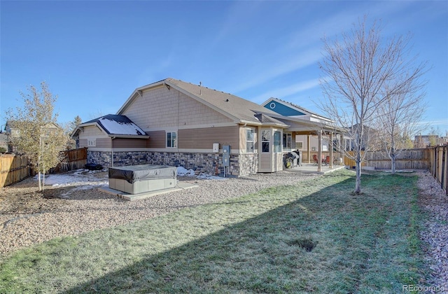 25525 E 1st Ave, Aurora, CO 80018 - rear view of property featuring stone siding, a fenced backyard, a patio area, and a hot tub