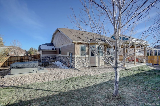 25525 E 1st Ave, Aurora, CO 80018 - back of house featuring a hot tub, a patio area, a fenced backyard, and stone siding