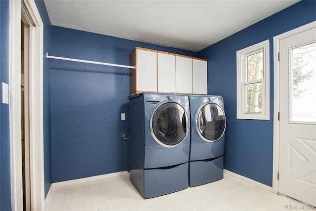 clothes washing area with a textured ceiling, cabinets, and separate washer and dryer