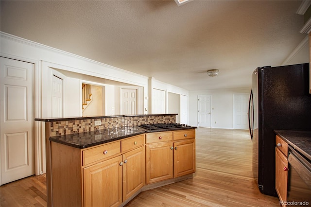 kitchen featuring dark stone counters, black appliances, light hardwood / wood-style flooring, and tasteful backsplash