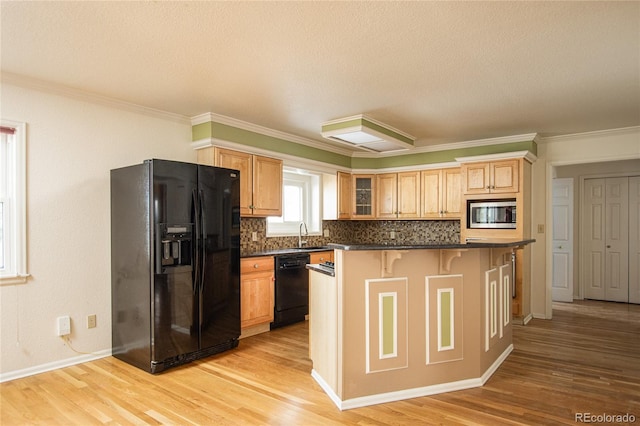 kitchen featuring a kitchen breakfast bar, light hardwood / wood-style floors, backsplash, black appliances, and crown molding