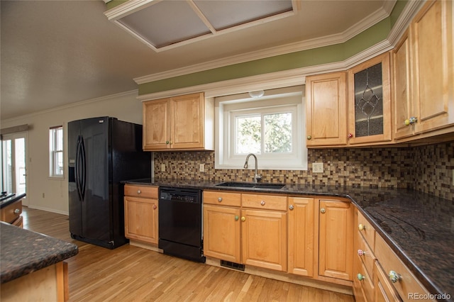 kitchen featuring sink, dark stone countertops, light wood-type flooring, backsplash, and black appliances