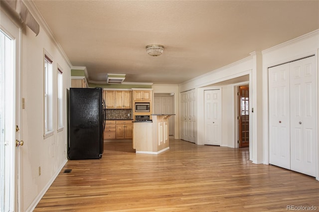 kitchen with black refrigerator, ornamental molding, stainless steel microwave, light hardwood / wood-style flooring, and tasteful backsplash