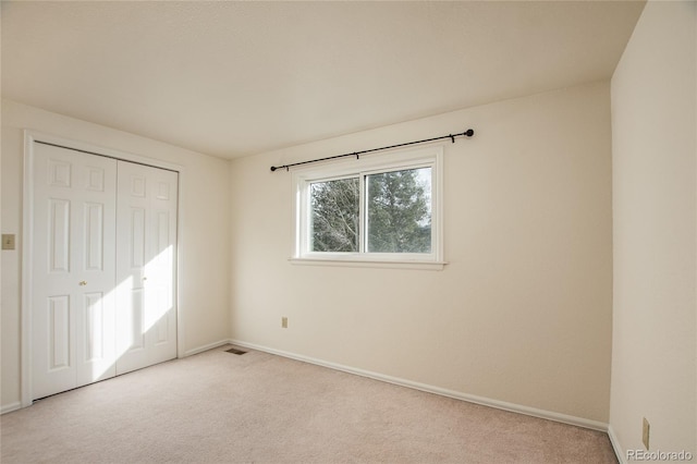 unfurnished bedroom with light colored carpet and a closet