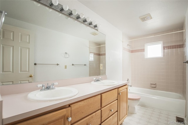 full bathroom with tiled shower / bath combo, vanity, and toilet