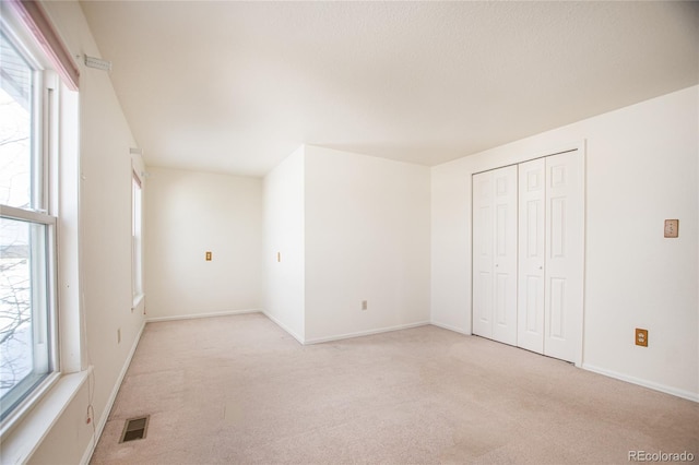 unfurnished bedroom featuring light colored carpet and a closet