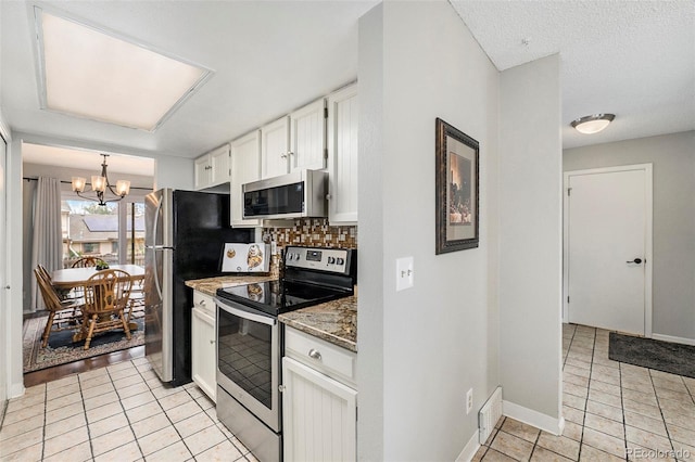 kitchen with decorative backsplash, baseboards, white cabinetry, a chandelier, and appliances with stainless steel finishes