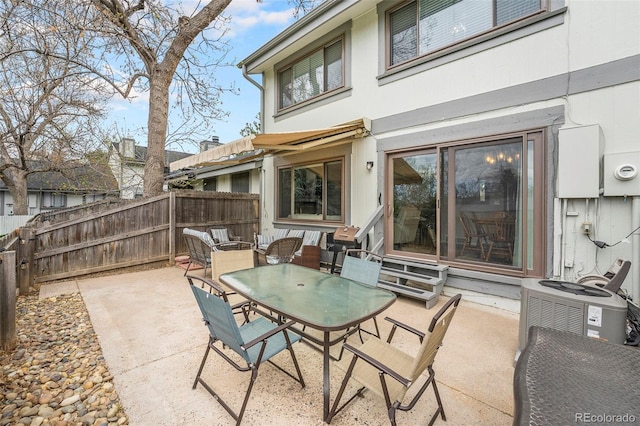 view of patio featuring entry steps, fence, outdoor dining area, and cooling unit