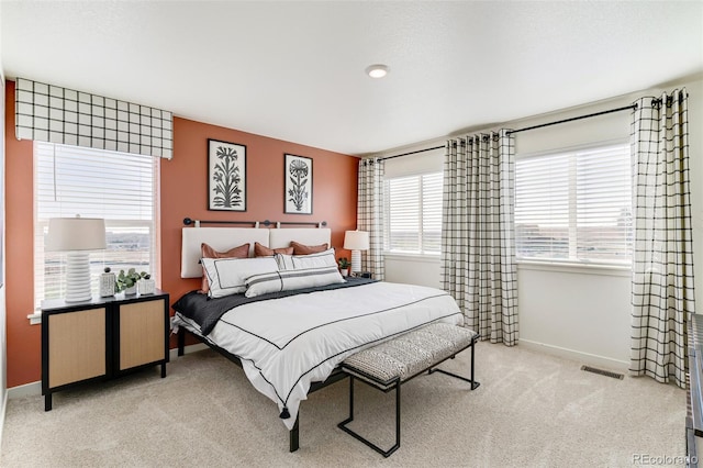 bedroom with multiple windows and light carpet