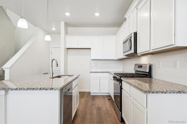 kitchen with light stone countertops, pendant lighting, stainless steel appliances, and white cabinetry