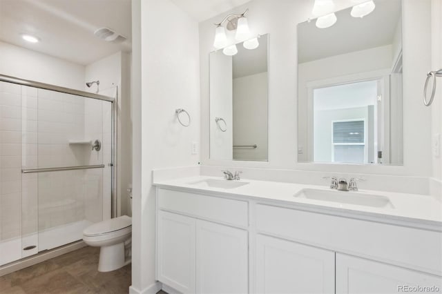 bathroom featuring vanity, a shower with shower door, and toilet