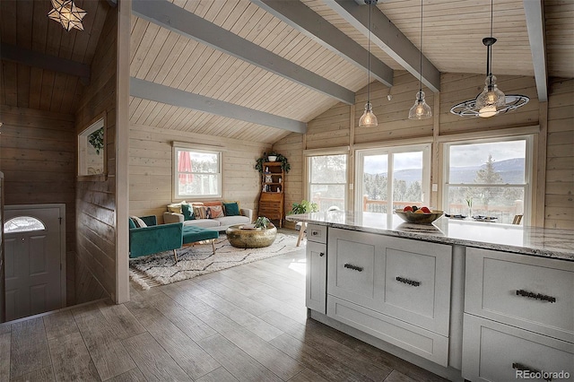 kitchen featuring dark hardwood / wood-style floors, pendant lighting, wood walls, vaulted ceiling with beams, and white cabinets