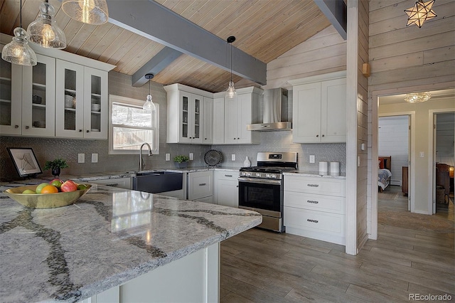 kitchen featuring stainless steel gas range, beam ceiling, white cabinets, decorative light fixtures, and wall chimney exhaust hood