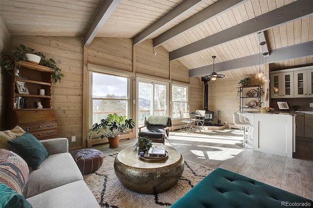 living room with lofted ceiling with beams, wooden ceiling, wooden walls, and light hardwood / wood-style flooring