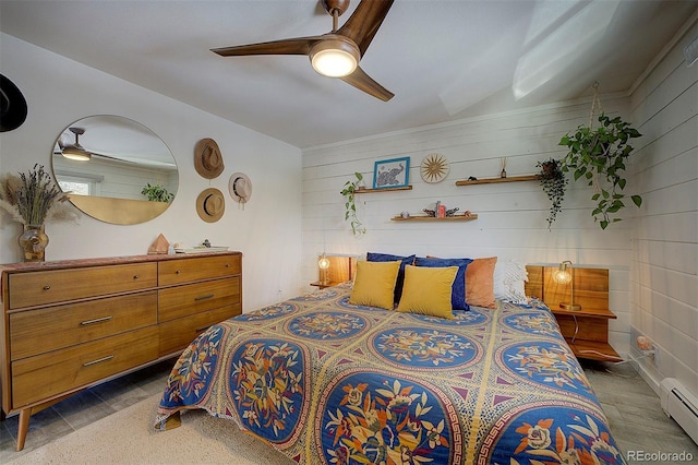 bedroom featuring a baseboard heating unit, ceiling fan, and wood walls