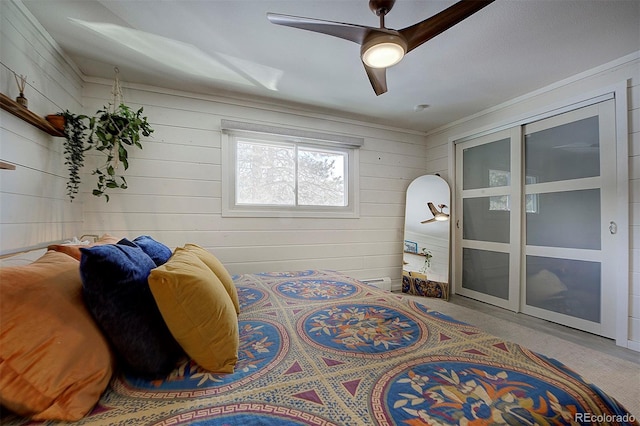 bedroom featuring ornamental molding, ceiling fan, and wood walls