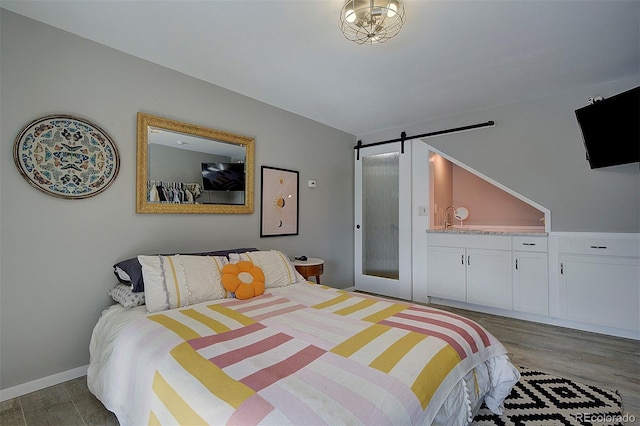 bedroom featuring a barn door and dark hardwood / wood-style floors