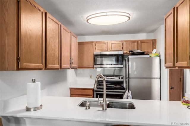 kitchen featuring a sink, stainless steel appliances, brown cabinetry, and light countertops