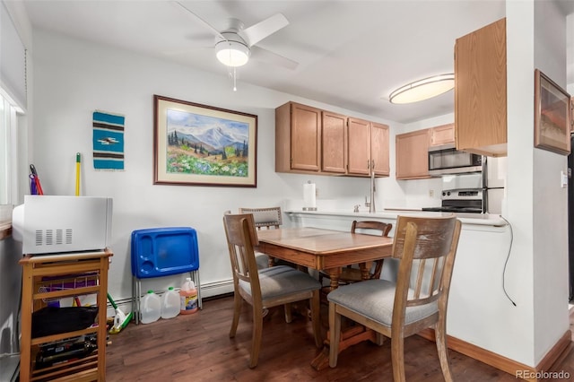 dining room with a baseboard heating unit, ceiling fan, wood finished floors, and baseboards