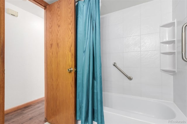 bathroom featuring shower / tub combo with curtain, baseboards, and wood finished floors