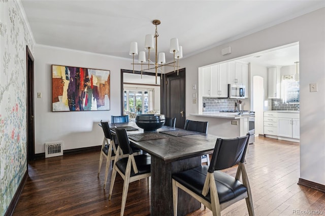 dining space featuring ornamental molding, dark wood-type flooring, and an inviting chandelier