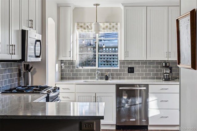 kitchen with appliances with stainless steel finishes, white cabinets, decorative light fixtures, backsplash, and sink