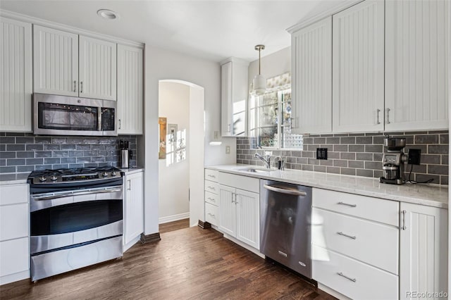 kitchen featuring white cabinets, stainless steel appliances, decorative light fixtures, and sink