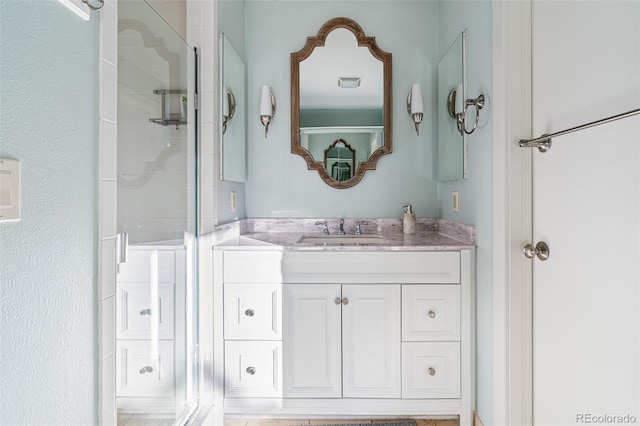 bathroom featuring a shower with door and vanity