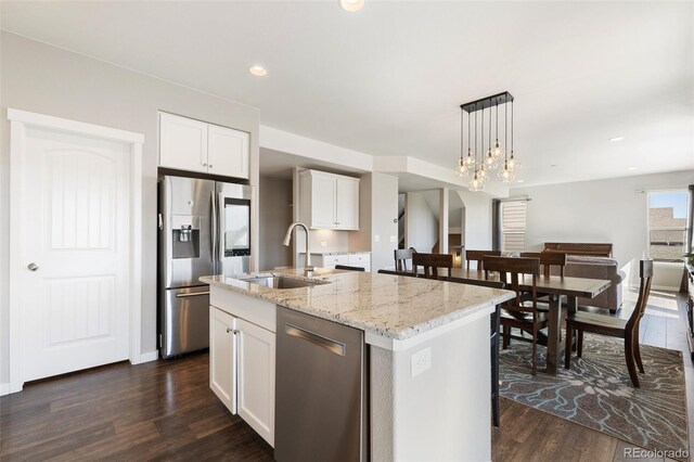 8235 Ryegate Way, Colorado Springs, CO 80908 - kitchen featuring appliances with stainless steel finishes, a sink, dark wood-style floors, hanging light fixtures, and an island with sink