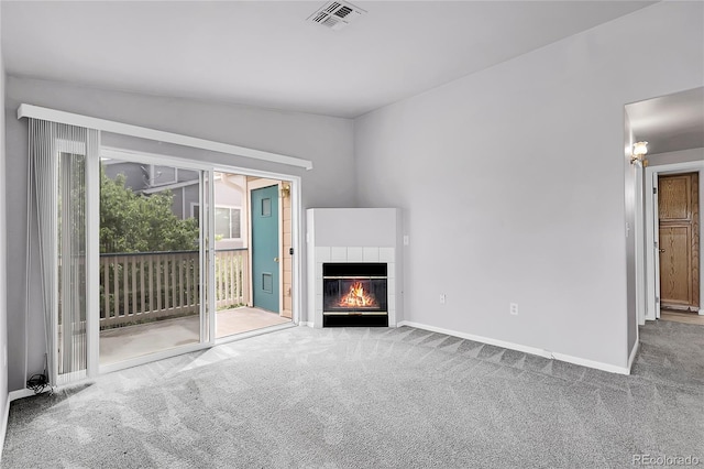 unfurnished living room with carpet floors, a tiled fireplace, and baseboards