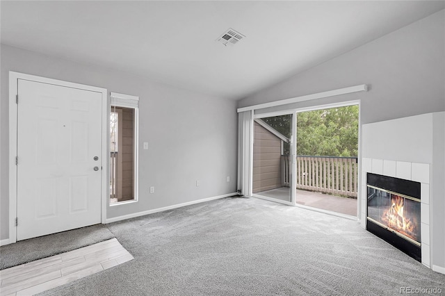 unfurnished living room with lofted ceiling, a tile fireplace, baseboards, and wood finished floors
