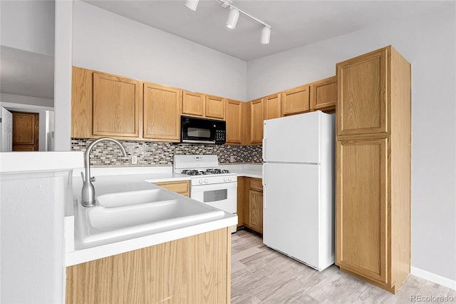 kitchen with white appliances, a sink, light countertops, decorative backsplash, and light wood finished floors