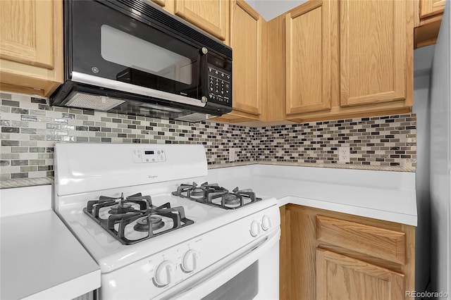 kitchen featuring black microwave, white gas range, light countertops, backsplash, and light brown cabinets