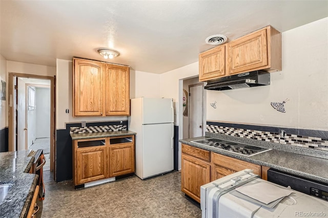 kitchen with cooktop, tasteful backsplash, visible vents, freestanding refrigerator, and under cabinet range hood