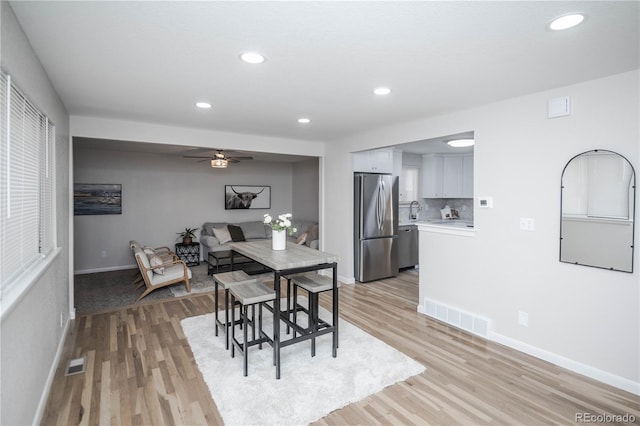 dining area with light wood-type flooring, ceiling fan, and sink