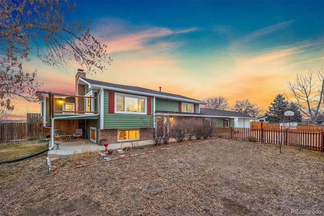 back house at dusk with a balcony and a patio