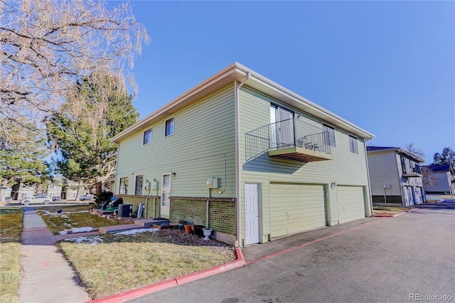 view of property exterior featuring central AC, a balcony, and a garage