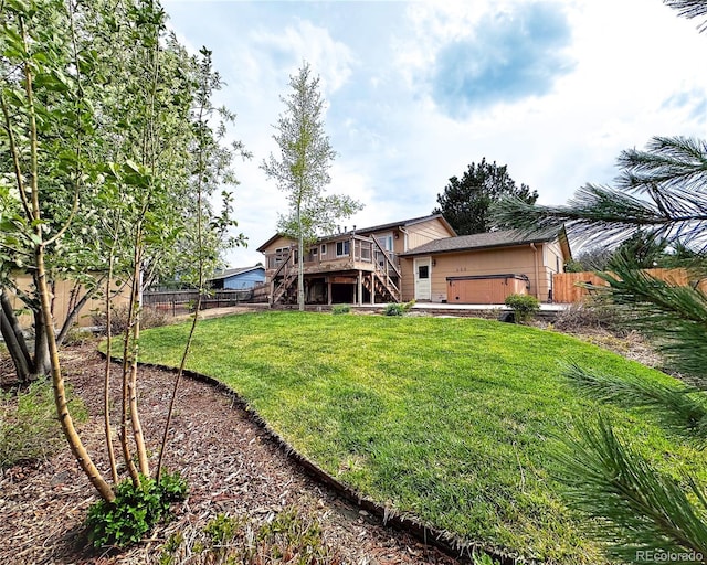 rear view of property with a wooden deck, a fenced backyard, stairs, a lawn, and a hot tub