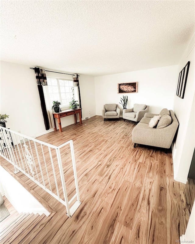 living area featuring stairs, a textured ceiling, and light wood-type flooring