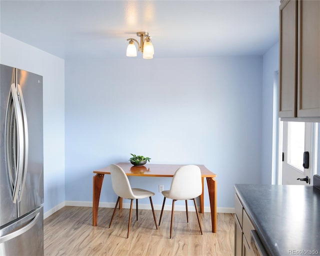 kitchen featuring freestanding refrigerator, baseboards, dark countertops, and light wood-style flooring