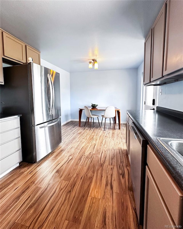kitchen with baseboards, dark countertops, appliances with stainless steel finishes, and light wood-style flooring