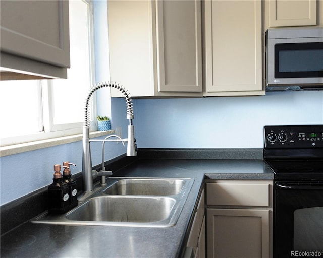 kitchen featuring electric range, dark countertops, stainless steel microwave, a sink, and gray cabinetry