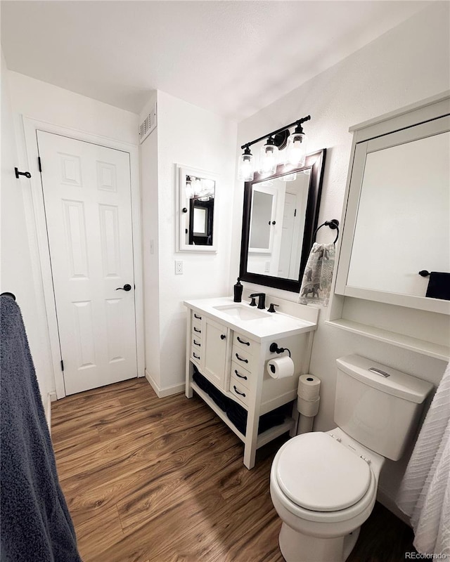 bathroom with visible vents, wood finished floors, vanity, baseboards, and toilet