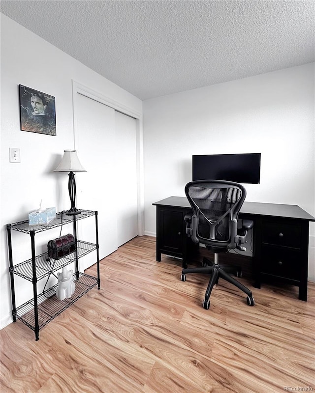 office area with light wood-type flooring and a textured ceiling