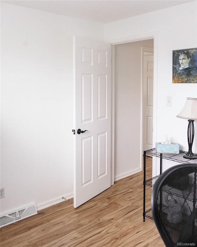 office area featuring baseboards, light wood-style flooring, and visible vents