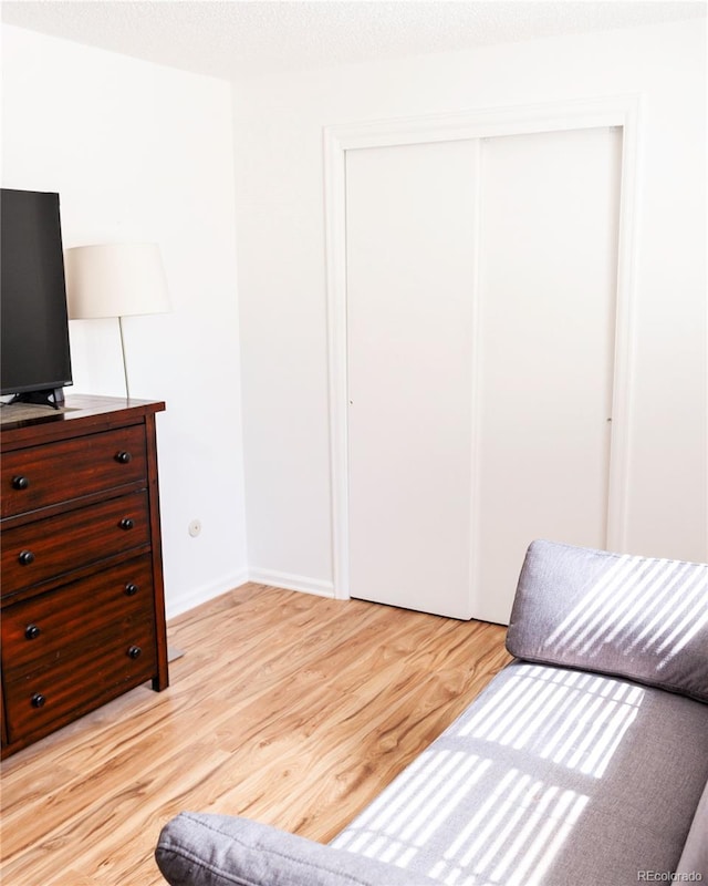 bedroom featuring a closet, light wood-style floors, and baseboards