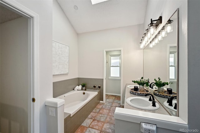 bathroom featuring a relaxing tiled tub, vanity, and vaulted ceiling