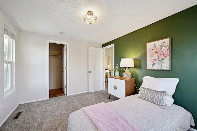 bedroom featuring a textured ceiling, carpet floors, a spacious closet, and a closet